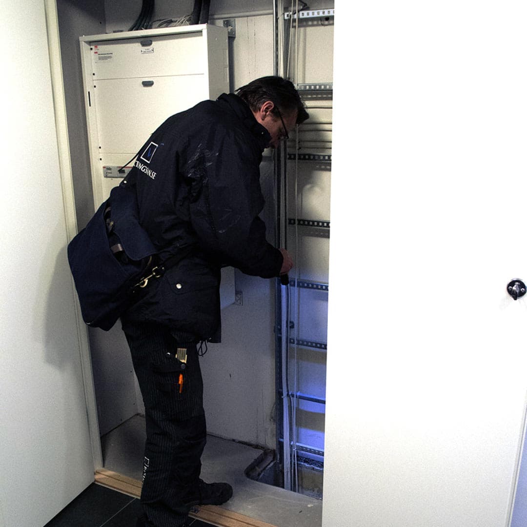Besiktningsman besiktigar tak på ett hus och pekar på fel